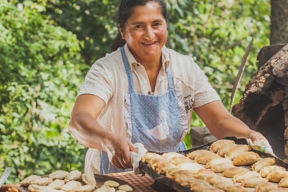 a smiling lady with a tray of empanadas in northern argentina