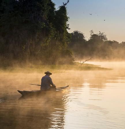 Brazil amazon man on boat sailing the river in the early morning