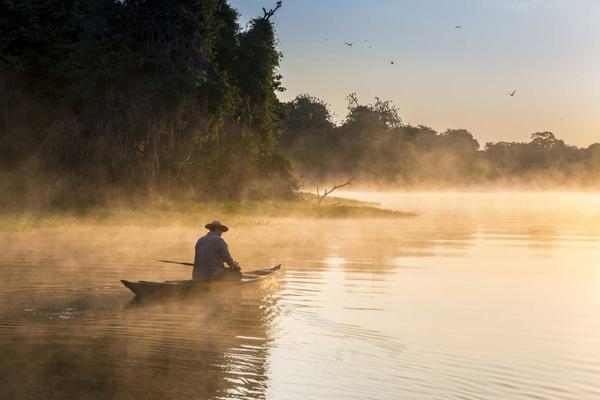 Brazil amazon man on boat sailing the river in the early morning