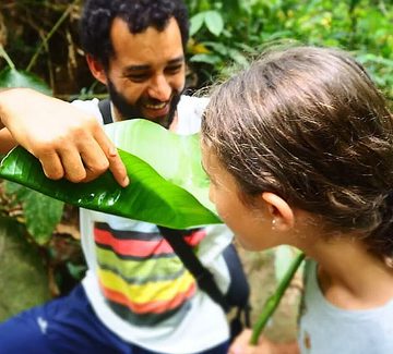 a guide gives a folded leaf to a girl to drink in the atlantic rainforest in brazil
