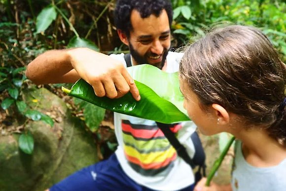 a guide gives a folded leaf to a girl to drink in the atlantic rainforest in brazil