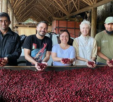 smiling hosts and visitors with red coffee cherries in brazil