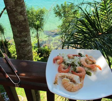 a plate of prawns and seafood with bbq tongs by the sea