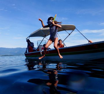 young girl jumps from a boat into the sea near paraty