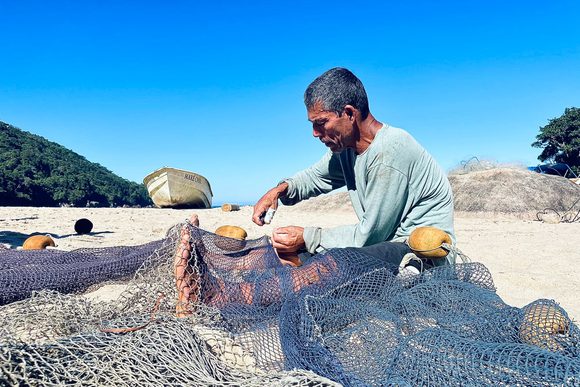 fisherman untangling their net on ponta negra beach