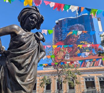 statue and colourful bunting below a huge mural in central rio