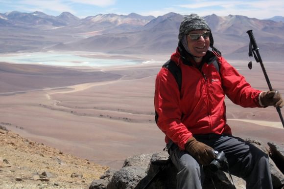 a guide in a red top smiles for the camera on top of the toco volcano in the atacama desert