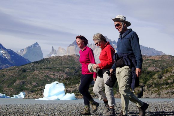 three adults walking along beach of lago grey