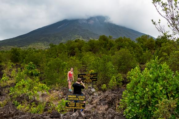 teenagers psoing for photo below arenal volcano