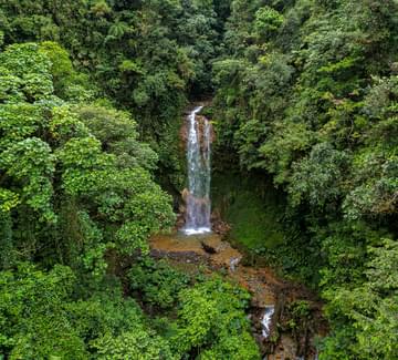 aerial view of a tall waterfall nestled in green forests in bajos del toro