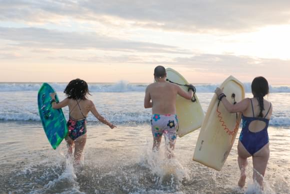 family running into waves on beach in costa rica