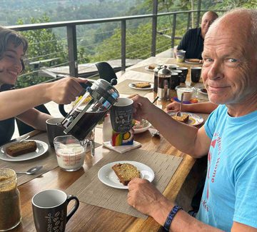 a grandparent smiles at the camera over breakfast on a hotel terrace in costa rica