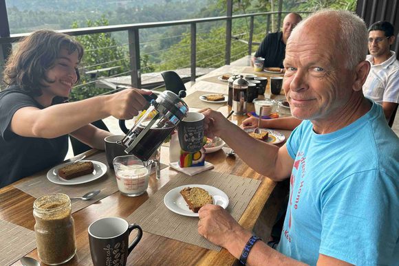 a grandparent smiles at the camera over breakfast on a hotel terrace in costa rica