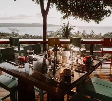 dinner tables arrange on a terrace overlooking the pacific ocean