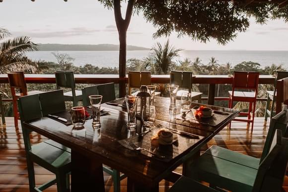 dinner tables arrange on a terrace overlooking the pacific ocean