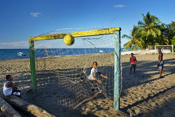 a group of young boys play football on a caribbean beach in costa rica