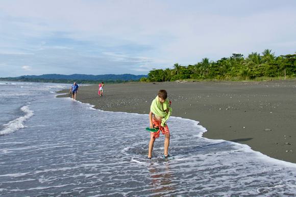 boys and grandfather walking on wild pacfic beach on the osa peninsula