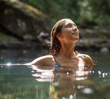 a close up photo of a lady swimming in a natural pool