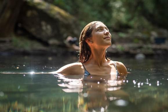 a close up photo of a lady swimming in a natural pool