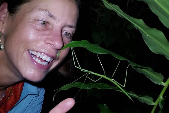 a lady excitidely points to a stick insect on a night walk in costa rica