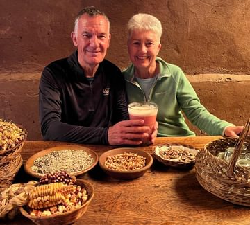 male and female travellers with typical peruvian food and a glass of chicha