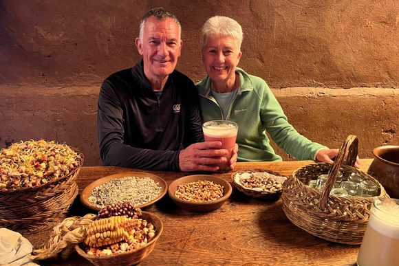 male and female travellers with typical peruvian food and a glass of chicha