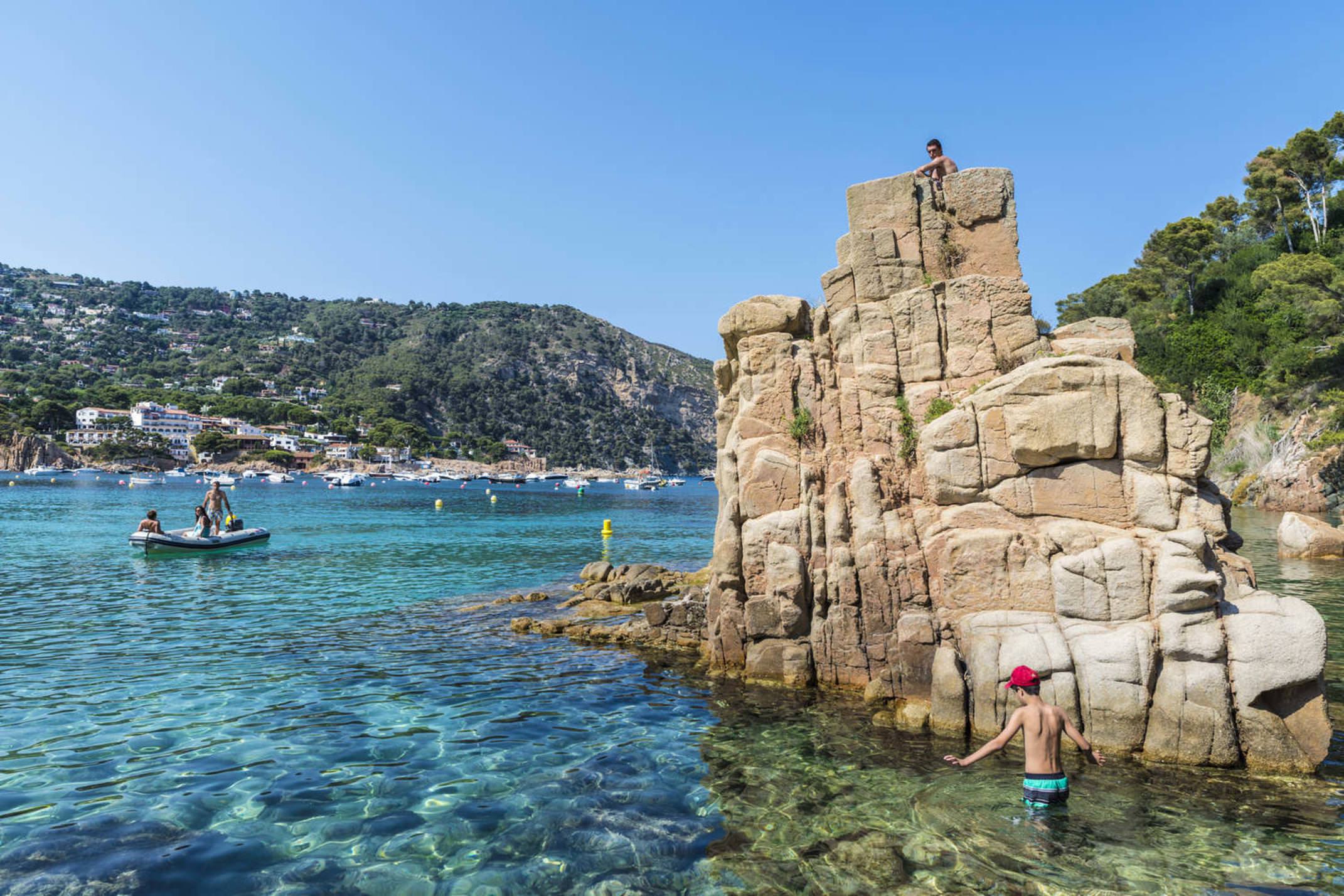 Spain catalonia aiguablava beach with sunbathers while a boat is heading to the beach in costa brava j2r