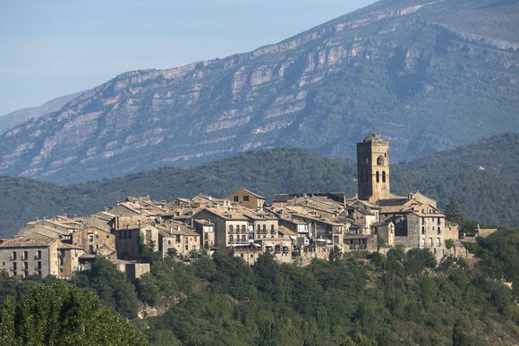 the medieval town of ainsa perched on a ridge in front of the pyrenees mountains